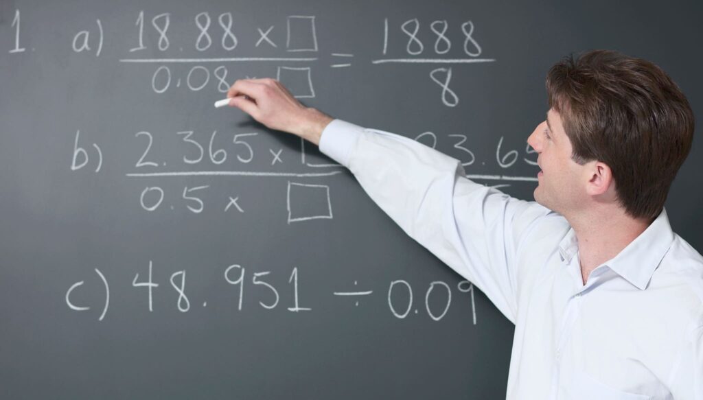 Maths tutor explaining mathematics at a blackboard